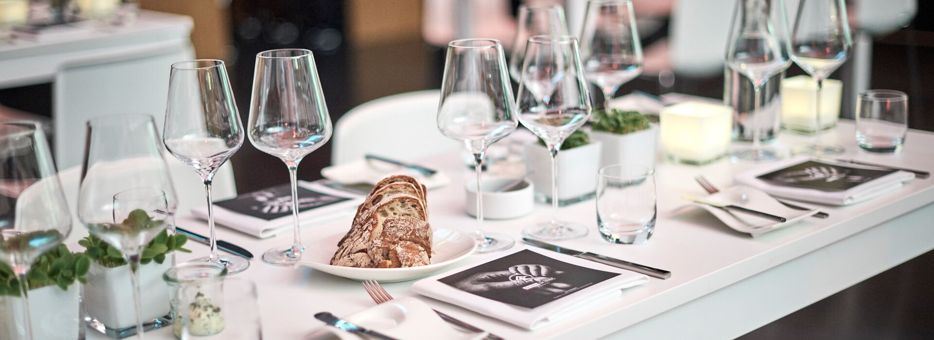 MIETMÜLLER im urbanharbor Ludwigsburg Banketttische mit Wein- und Wasserglas Blumen-Dekoration und Brot-Teller