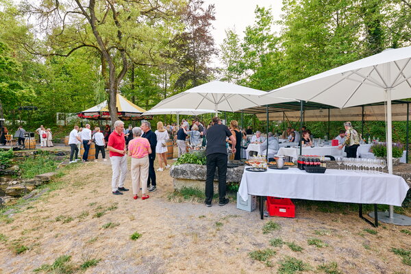Seefest Gäste genießen eine Veranstaltung im Freien mit Buffet und Sitzgelegenheiten am Wasser, umgeben von Natur.