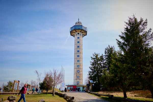 USU SPRING UP! in Willingen Hoher Aussichtsturm mit Glasaufsatz auf einem Hügel, umgeben von Bäumen und blauem Himmel