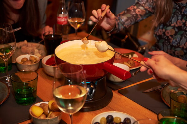 Incentive Sölden Gemeinsames genießen von Käsefondue an einem Tisch mit Wein und Beilagen