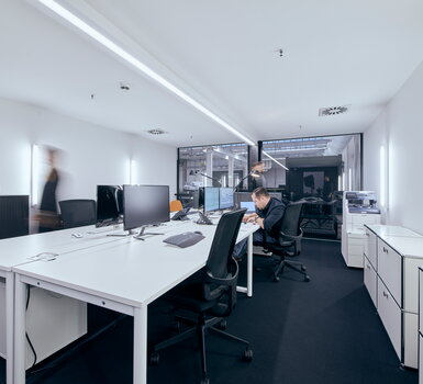 Helles, modernes Büro von Müller Live-Kommunikation mit Mitarbeitern, die an Schreibtischen mit Computern arbeiten