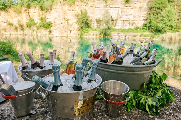 Seefest Champagner-Kühler voller Champagner- und Weinflaschen am malerischen Ufer eines Steinbruchsee