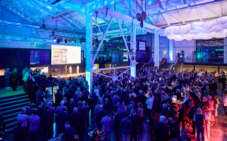 IHK Jahresempfang urbanharbor Ludwigsburg Menschenmenge bei einem Event mit bunten Lichtern und Präsentationen auf der Bühne