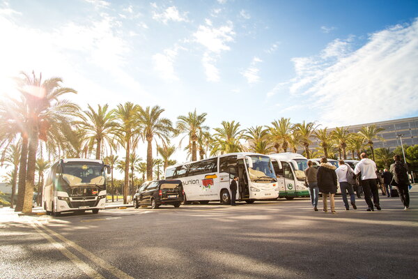 Kick-off für USU auf Mallorca mit modernen Reisebussen die unter Palmen parken während Passagiere einsteigen und aussteigen
