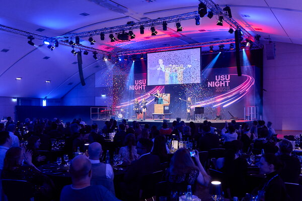 USU SPRING UP! in Willingen Bühne bei der "USU NIGHT 2025" mit Konfetti, Künstlern und "USU NIGHT 2025"-Logo im Hintergrund