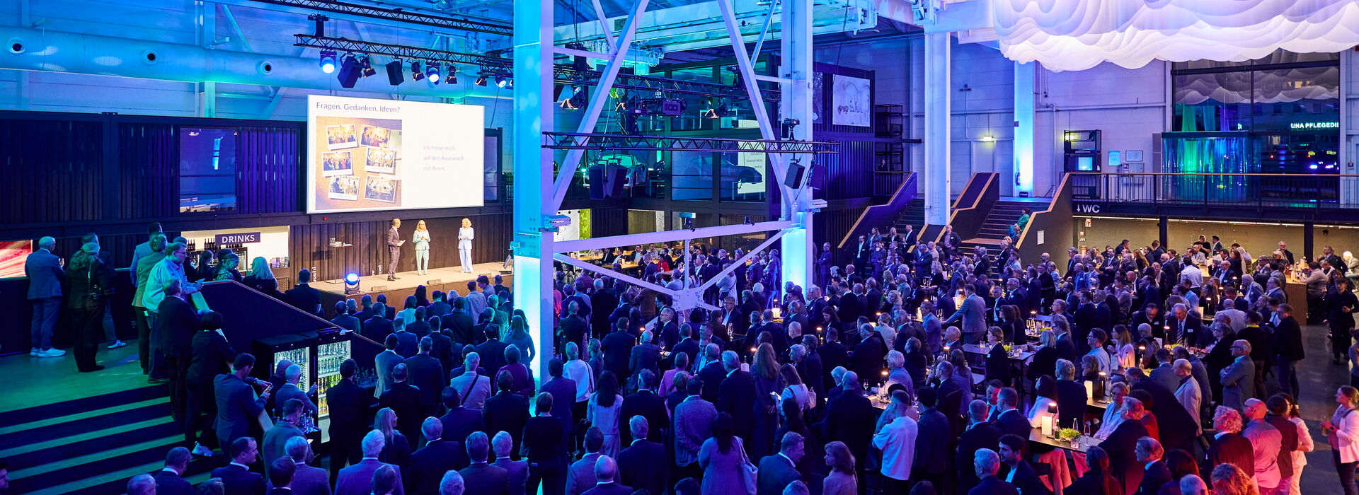 IHK Jahresempfang urbanharbor Ludwigsburg Menschenmenge bei einem Event mit bunten Lichtern und Präsentationen auf der Bühne