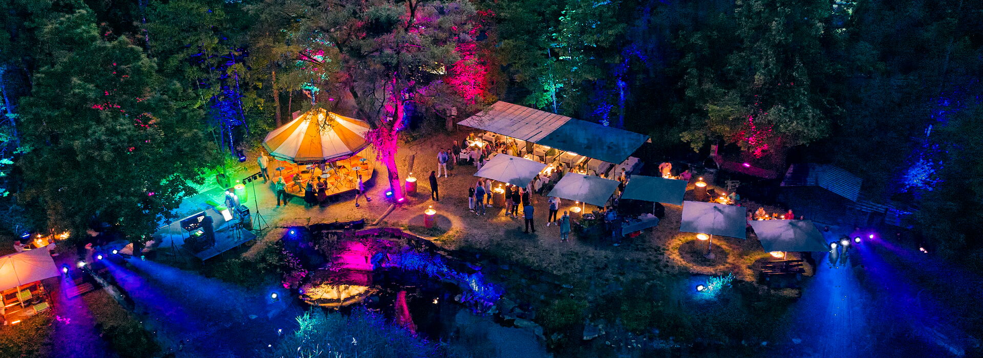 Seefest bei Nacht mit beleuchteten Ufer mit bunten Lichtern, Karussell und einer festlichen Atmosphäre inmitten von Bäumen