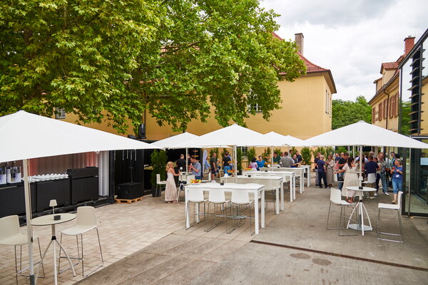 Kongress & Sommerfest Wolters Kluwer im Scala Ehrenhof eine belebte Außenveranstaltung mit Tischen und Sonnenschirmen