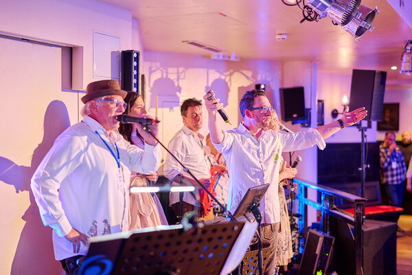 USU SPRING UP! in Willingen Band in weißen Hemden und Trachtenkleidung performt auf einer Bühne mit Mikrofonen und Scheinwerfern