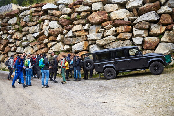 Incentive Sölden Gruppe von Wanderern und ein schwarzer Geländewagen zur Einweisung vor einer riesigen Steinmauer