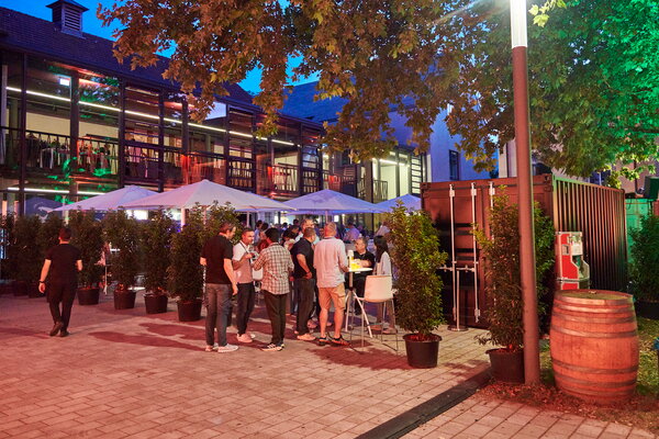 Kongress & Sommerfest Wolters Kluwer Scala Ludwigsburg im Ehrenhof mit beleuchteten Bäumen und Menschen, die sich unterhalten