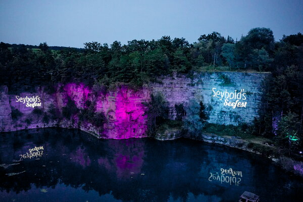 Seefest Felswand, beleuchtet mit bunten Lichtern, auf der "Seybold's Seefest" projiziert wird, mit Spiegelung im Wasser